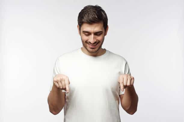 Young pointing down with fingers, isolated on gray background